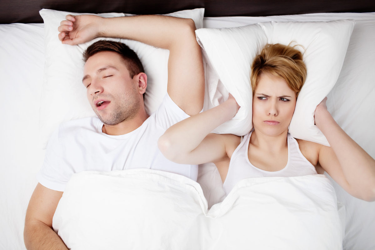 Snoring man and young woman. Couple sleeping in bed.