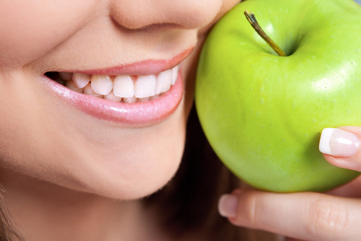 Woman holding Green Apple with Healthy Teeth and Glowing Smile - Skyline Dental